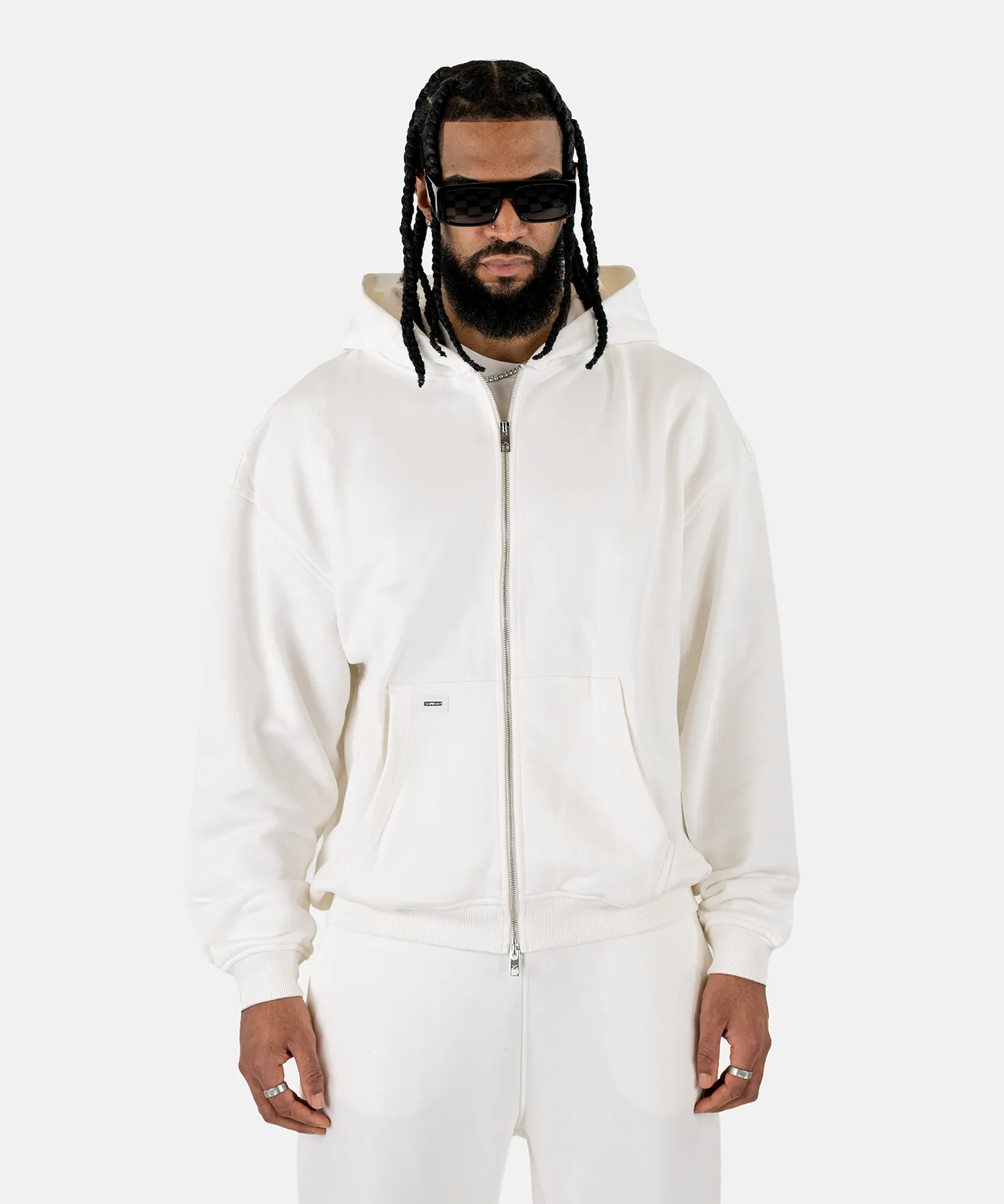 Vorderansicht eines männlichen Models, das den Squeqo Essential Oversized Zip Hoodie in Off-White trägt.