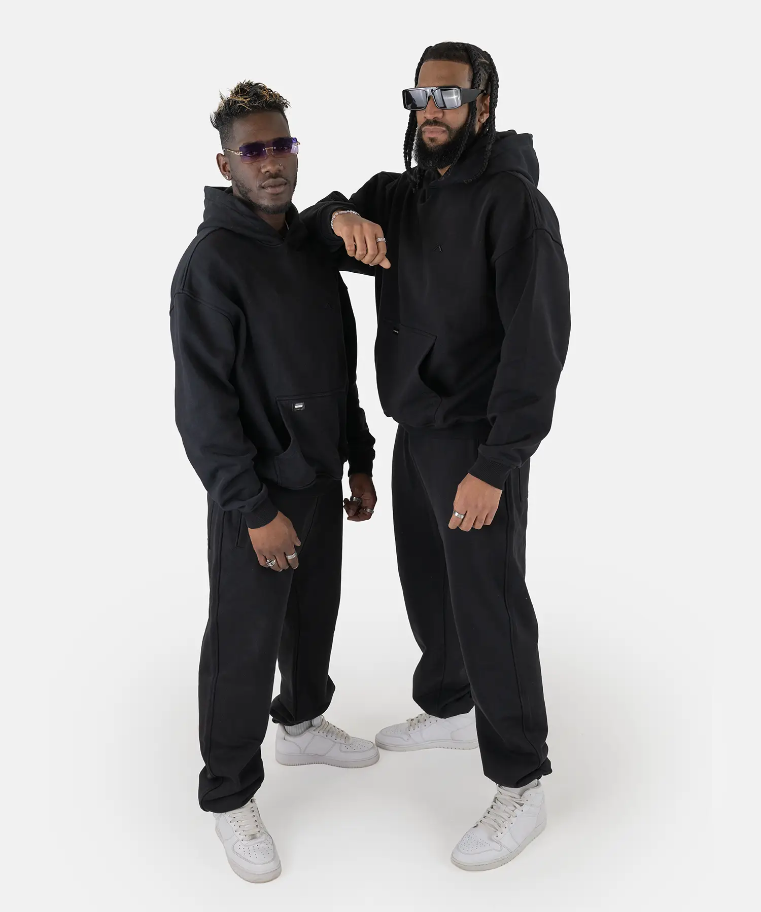 Zwei Models tragen den SQUEQO Oversized Hoodie in Schwarz und demonstrieren die vielseitige Unisex-Passform und moderne Styling-Möglichkeiten.