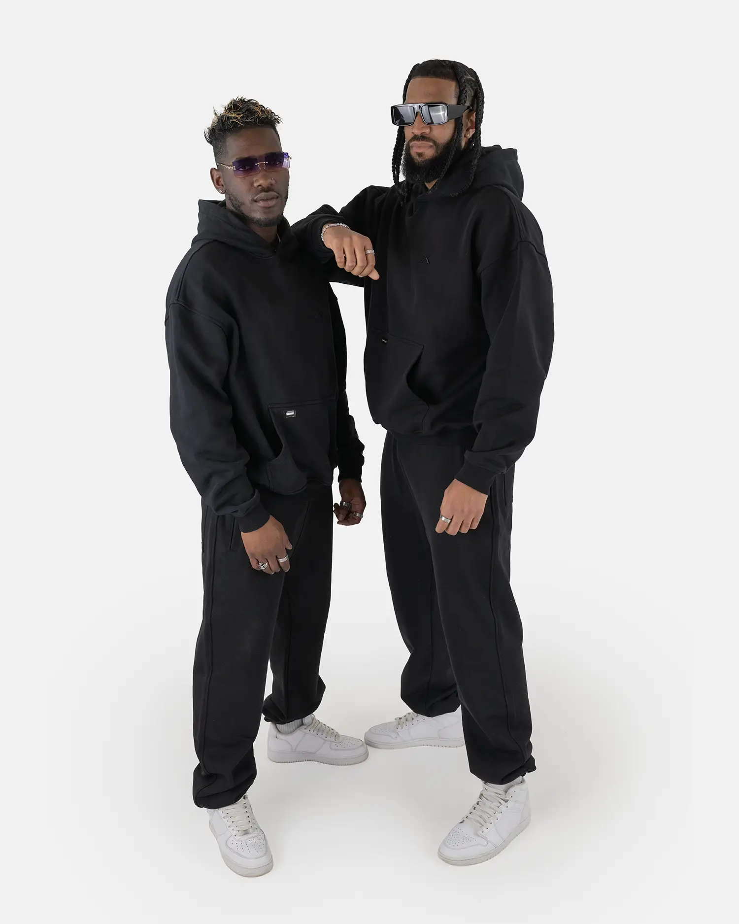 Zwei Models tragen den SQUEQO Oversized Hoodie in Schwarz und demonstrieren die vielseitige Unisex-Passform und moderne Styling-Möglichkeiten.