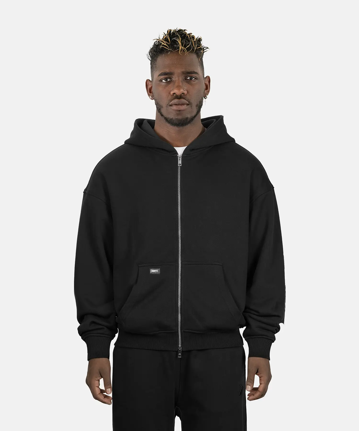 Model trägt SQUEQO Oversized Zip Hoodie in Schwarz