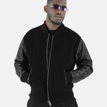 Studioporträt eines Mannes, der die schwarze SQUEQO Bomberjacke mit Lederärmeln trägt und mit Sonnenbrille selbstbewusst in die Kamera blickt.