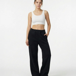 Model trägt die schwarze Elodie Sweatpant im Stacked-Look mit Extra-Länge und typischem Faltenwurf am Knöchel.