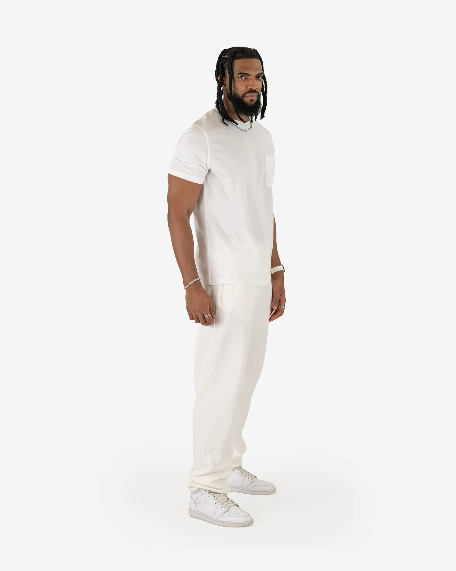 Seitenansicht eines männlichen Models, das das Squeqo Basic T-Shirt mit Brusttasche in Off-White aus Baumwolle trägt.