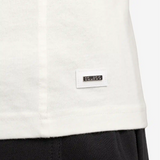 Nahaufnahme des gewebten Squeqo Logo-Labels am Saum des Off-White Basic T-Shirts.