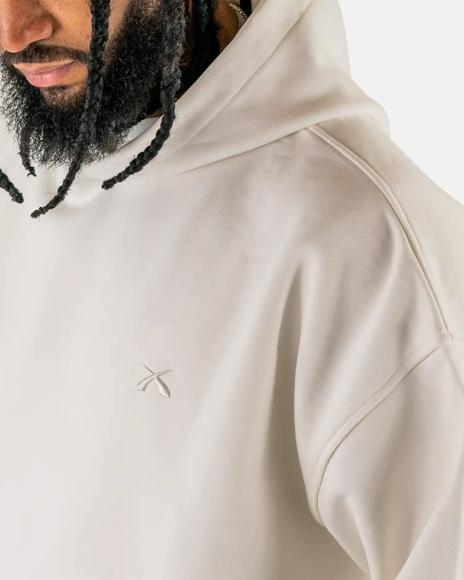 Detailaufnahme der überschnittenen Schulternaht und des gestickten Logos am Squeqo Essential Oversized Hoodie.
