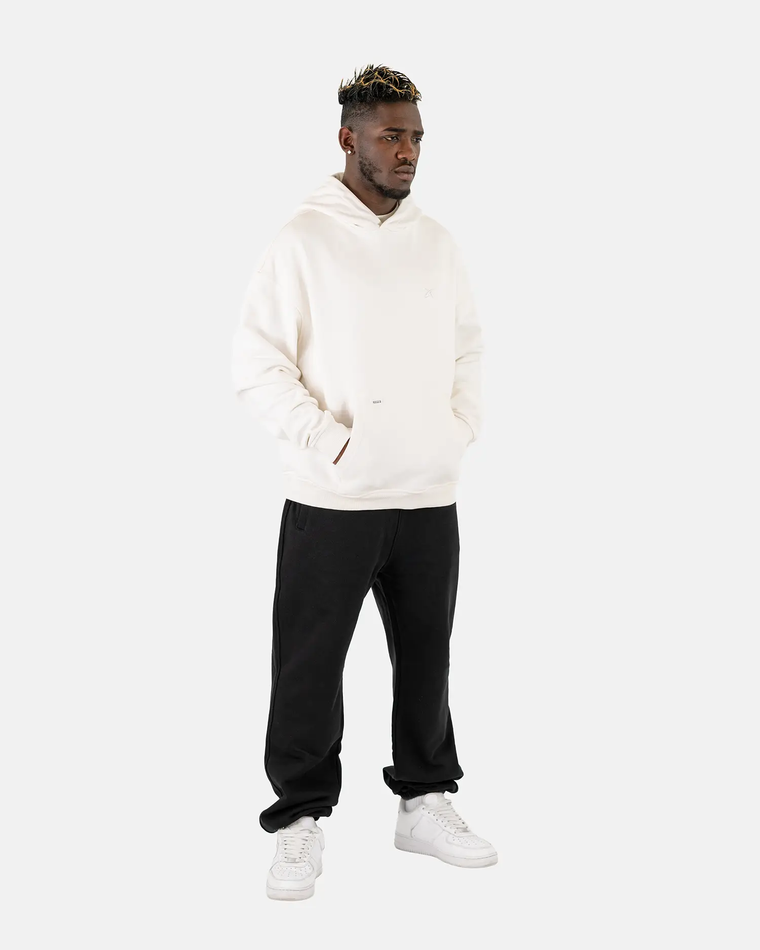 Ein männliches Model trägt den Squeqo Zip Hoodie in Off-White als Teil eines lässigen Streetwear-Looks.