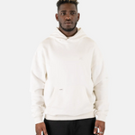 Vorderansicht eines männlichen Models, das den Squeqo Essential Oversized Hoodie in Off-White trägt.