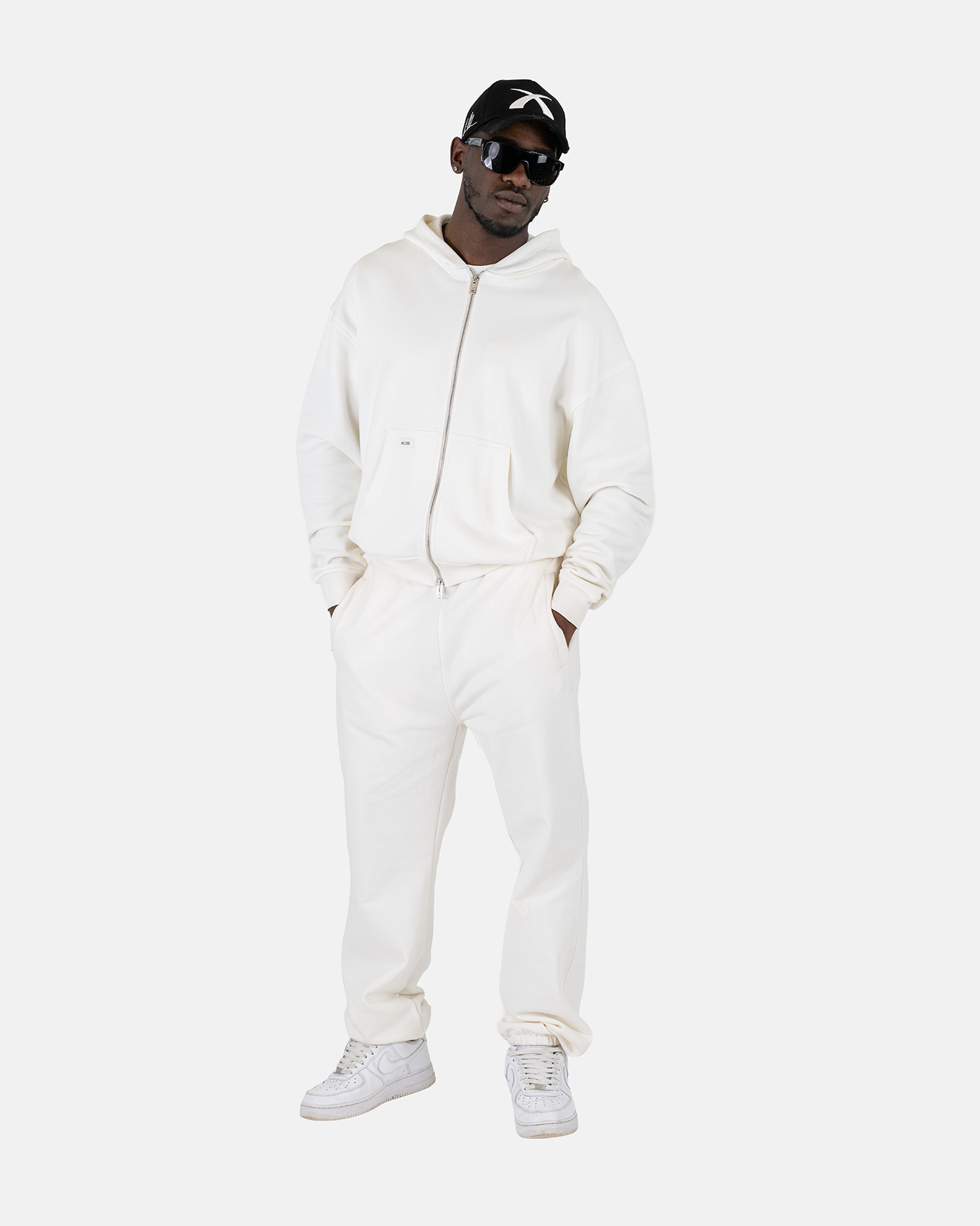 Ein männliches Model trägt den Squeqo Zip Hoodie in Off-White als Teil eines lässigen Streetwear-Looks.