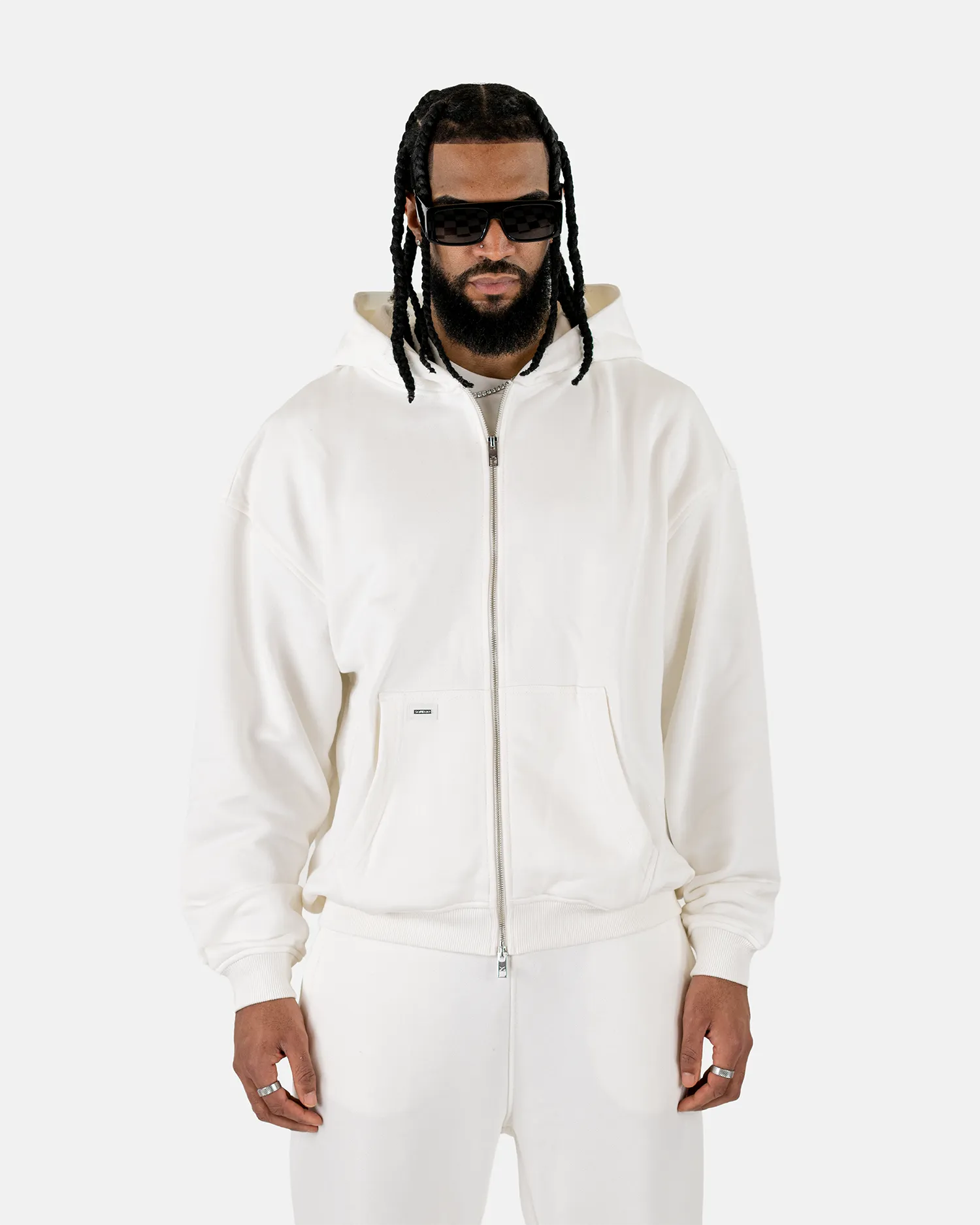 Vorderansicht eines männlichen Models, das den Squeqo Essential Oversized Zip Hoodie in Off-White trägt.