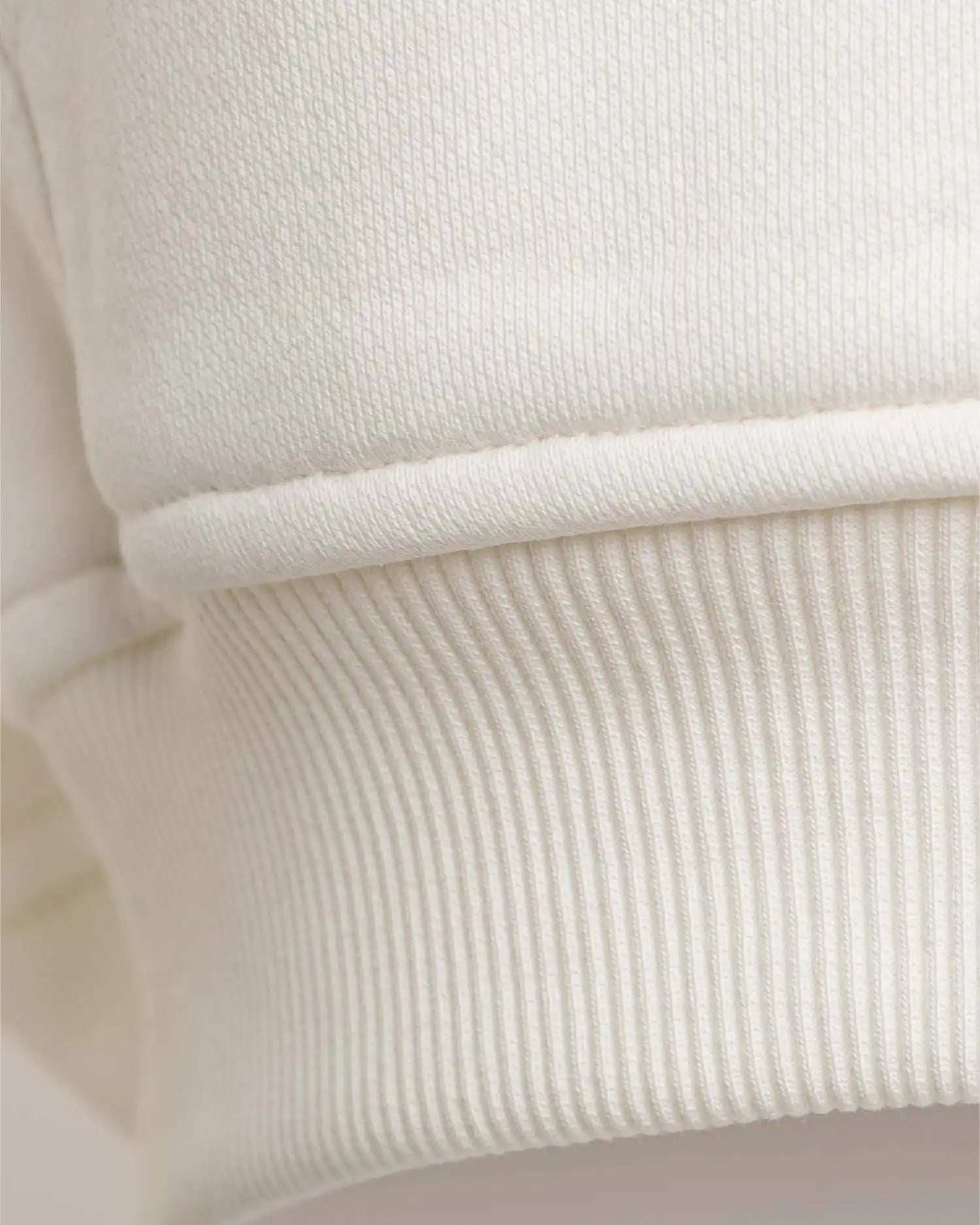 Detailaufnahme der elastischen Rippbündchen am Saum des Squeqo Zip Hoodies aus Baumwolle.