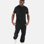 Ein männliches Model in einem kompletten schwarzen Outfit mit dem Squeqo Essential Pocket T-Shirt.