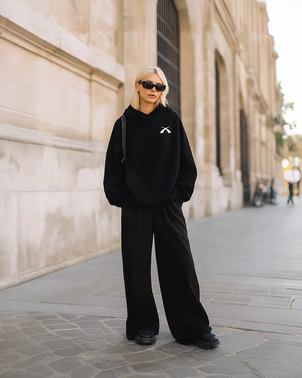 Model trägt den schwarzen SQUEQO Oversized Icon Hoodie (Fit 02) in einem urbanen Street-Style-Look.