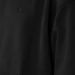 Makro-Detailaufnahme des hochwertigen, Ton-in-Ton gehaltenen 3D-Logo-Sticks auf der Brust des schwarzen SQUEQO Oversized Hoodies.
