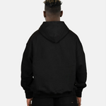 Rückansicht des schwarzen SQUEQO Oversized Hoodies, getragen von einem Model. Die cleane Rückenpartie und die Crossover-Kapuze werden gezeigt.