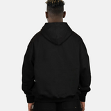 Rückansicht des schwarzen SQUEQO Oversized Hoodies, getragen von einem Model. Die cleane Rückenpartie und die Crossover-Kapuze werden gezeigt.