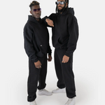 Zwei Models tragen den SQUEQO Oversized Hoodie in Schwarz und demonstrieren die vielseitige Unisex-Passform und moderne Styling-Möglichkeiten.