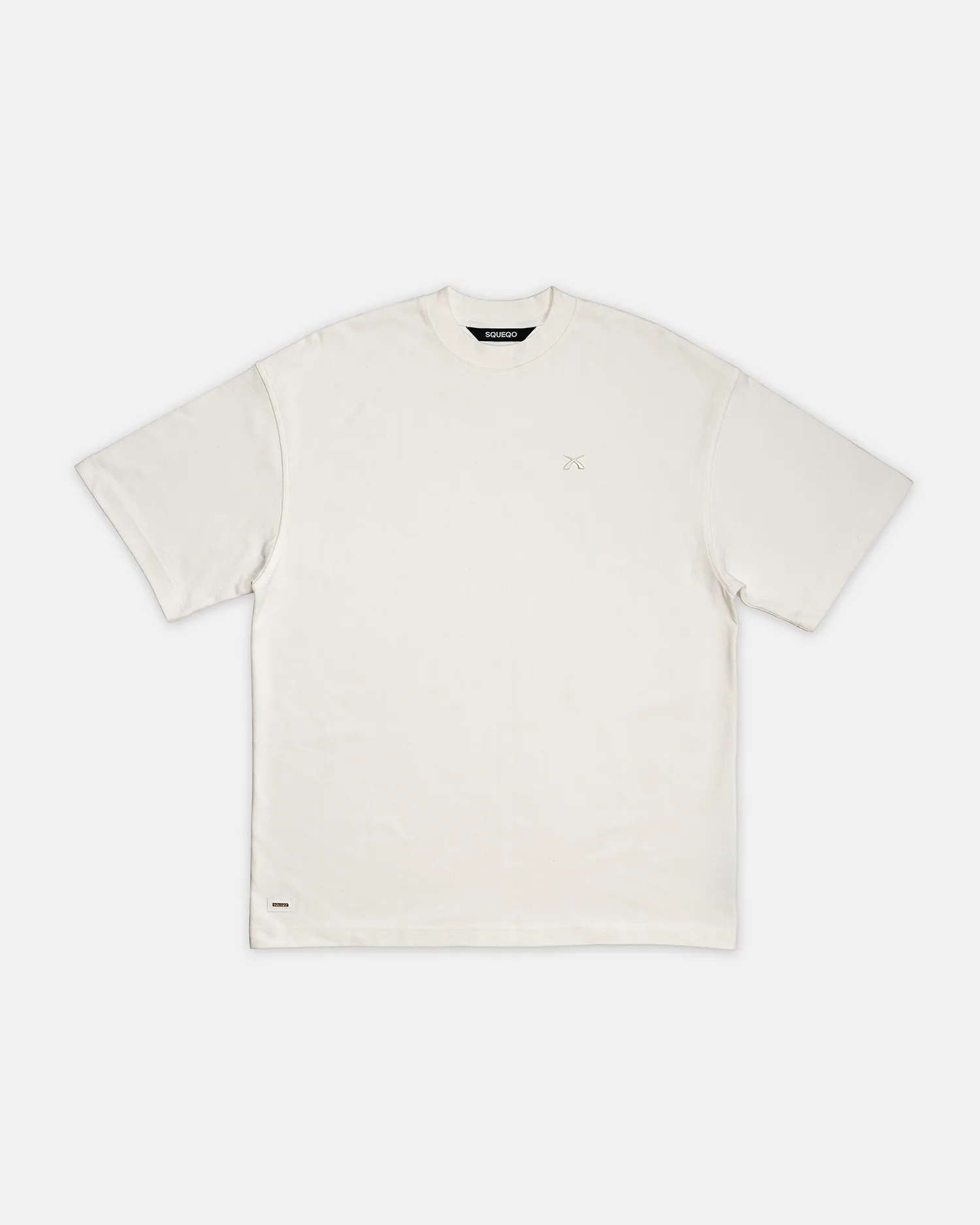 Flachgelegtes SQUEQO Oversized T-Shirt in Off-White, das die Gesamtform, den Oversized-Schnitt und das Nackenlabel zeigt.