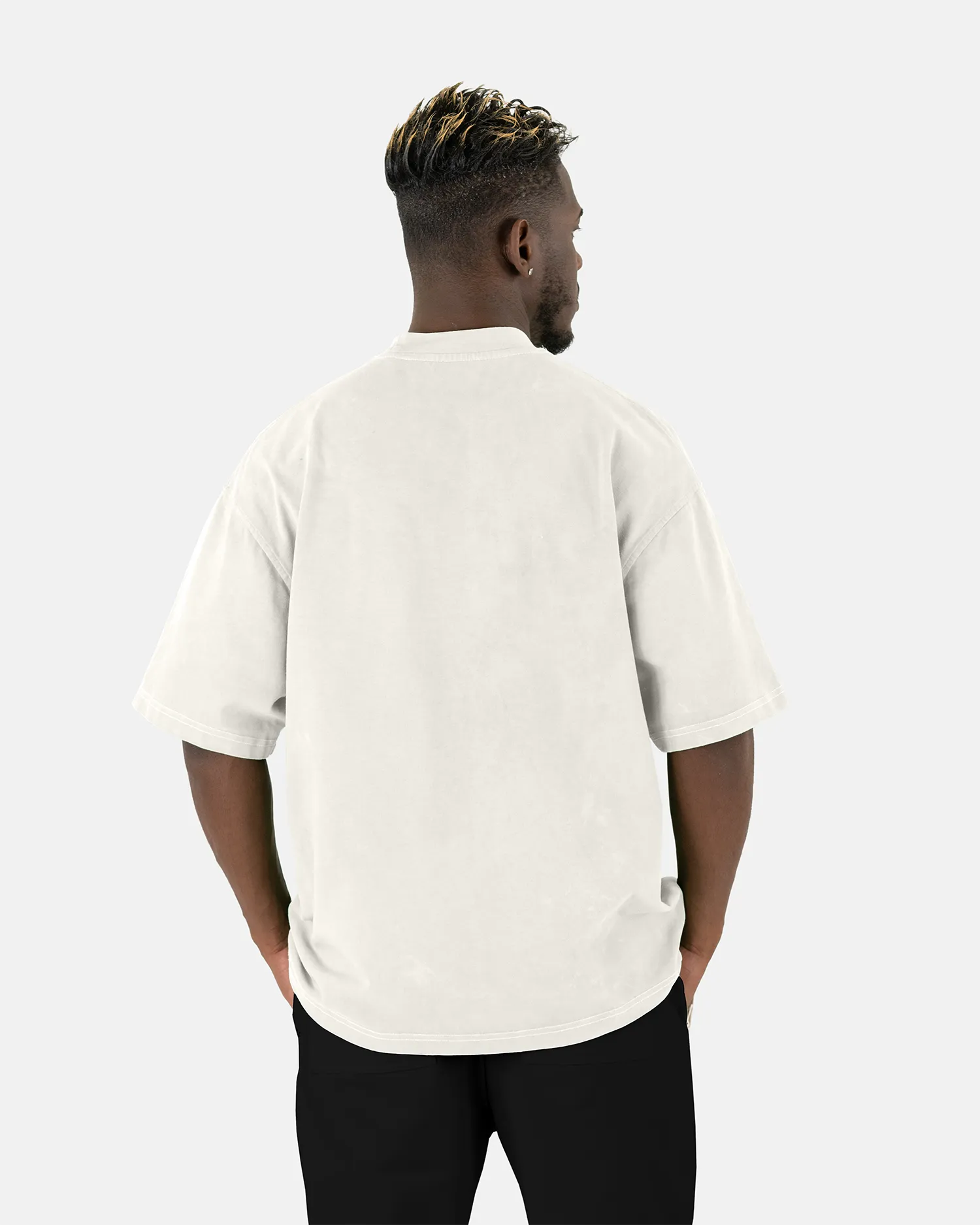 Rückenansicht eines männlichen Models, das das SQUEQO Oversized T-Shirt in Off-White trägt und die weite Oversized-Passform zeigt.