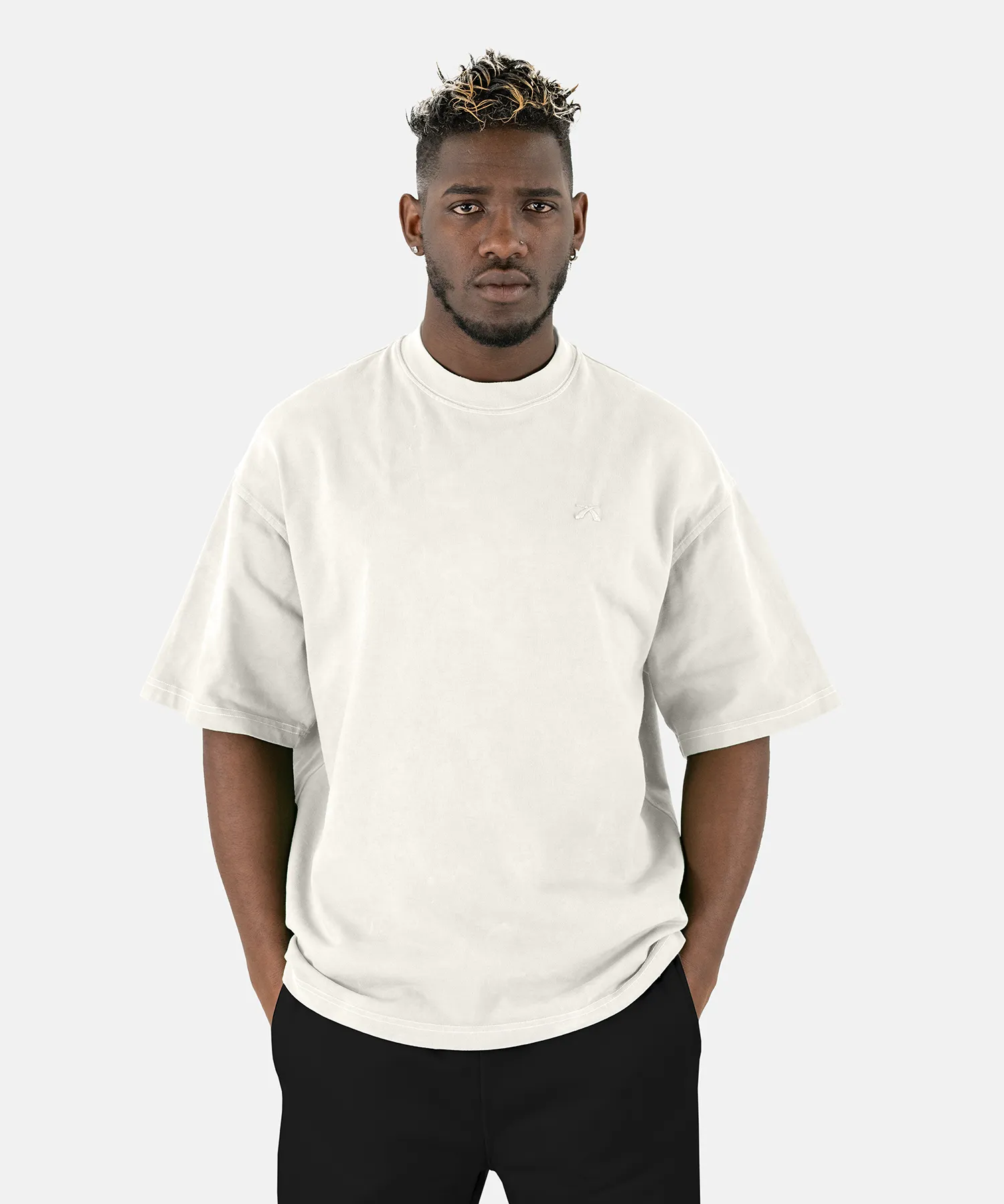 Vorderansicht eines männlichen Models, das das SQUEQO Oversized T-Shirt in Off-White mit dezentem Logo-Stick auf der Brust trägt.