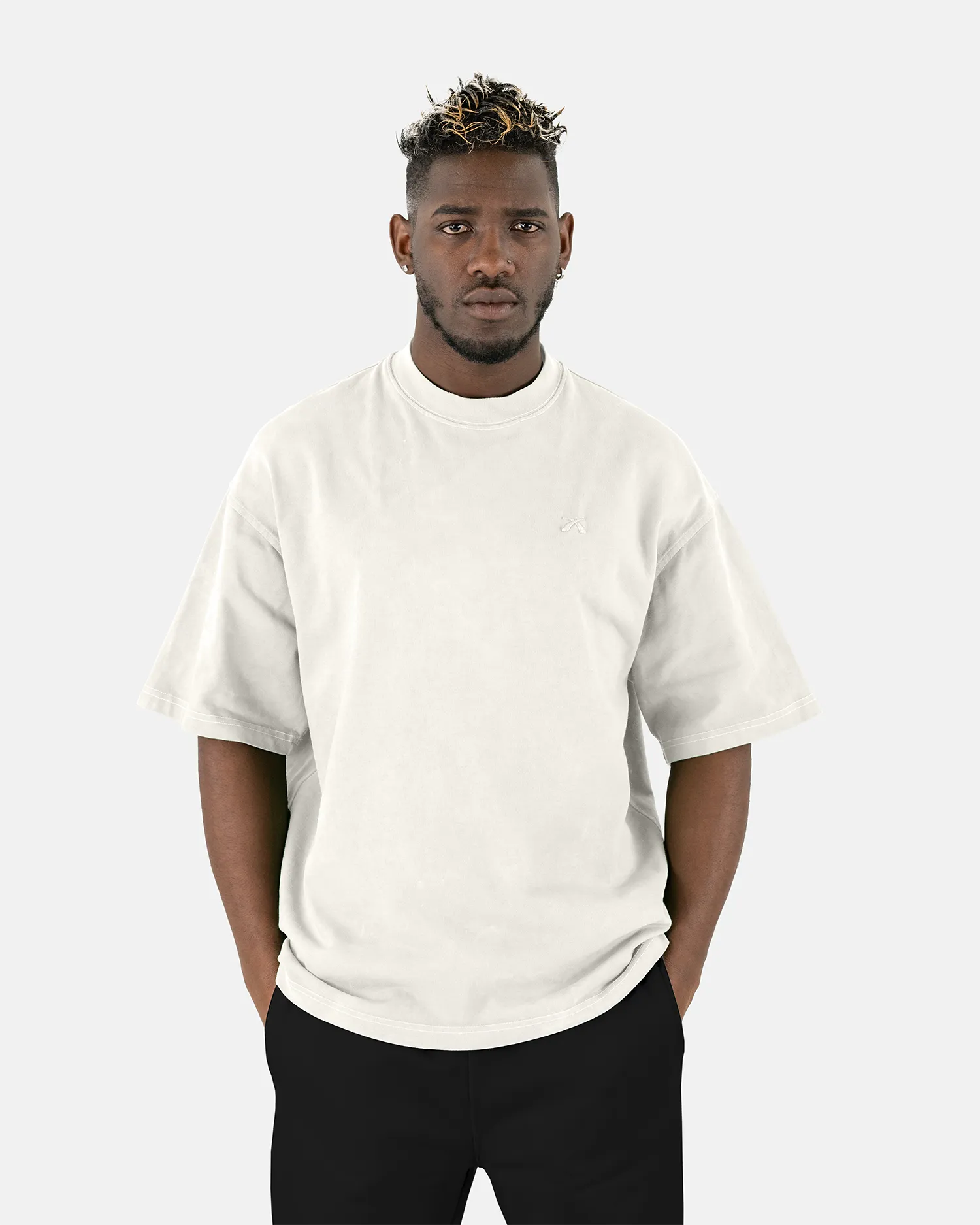 Vorderansicht eines männlichen Models, das das SQUEQO Oversized T-Shirt in Off-White mit dezentem Logo-Stick auf der Brust trägt.
