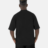 Rückenansicht eines Models, das das schwarze SQUEQO Oversized T-Shirt trägt und die weite Oversized-Passform zeigt.