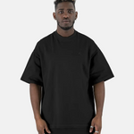 Vorderansicht eines Models, das das schwarze SQUEQO Oversized T-Shirt mit dezentem, Ton-in-Ton gesticktem Logo auf der Brust trägt.