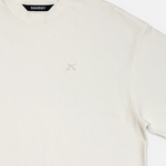 Detailaufnahme des SQUEQO T-Shirts in Off-White, die die doppelt verstärkten Nähte am Ärmel und die hochwertige Logo-Stickerei auf der Brust zeigt.